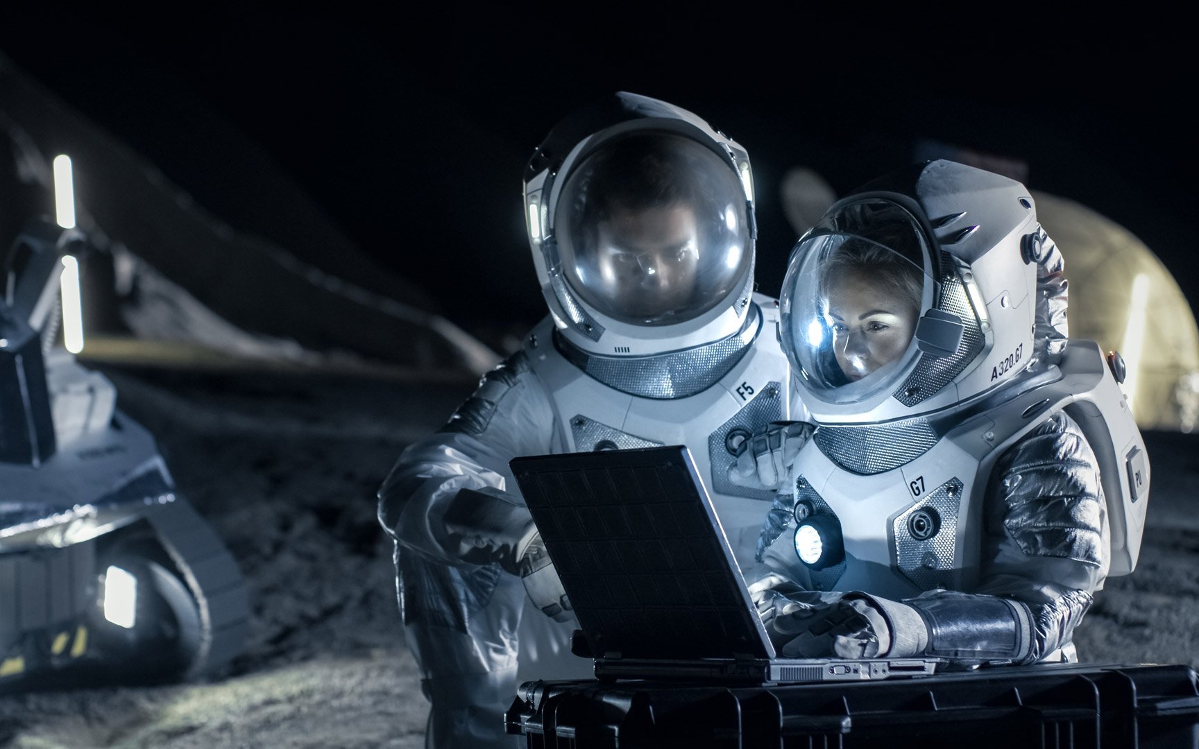 Zwei Astronauten, die Weltraumanzüge tragen, arbeiten auf einem Laptop, erforschen neu entdeckte Planeten und senden Signale an die Erde. Raumfahrt, Interstellar Exploration und Kolonialisierung Konzept.