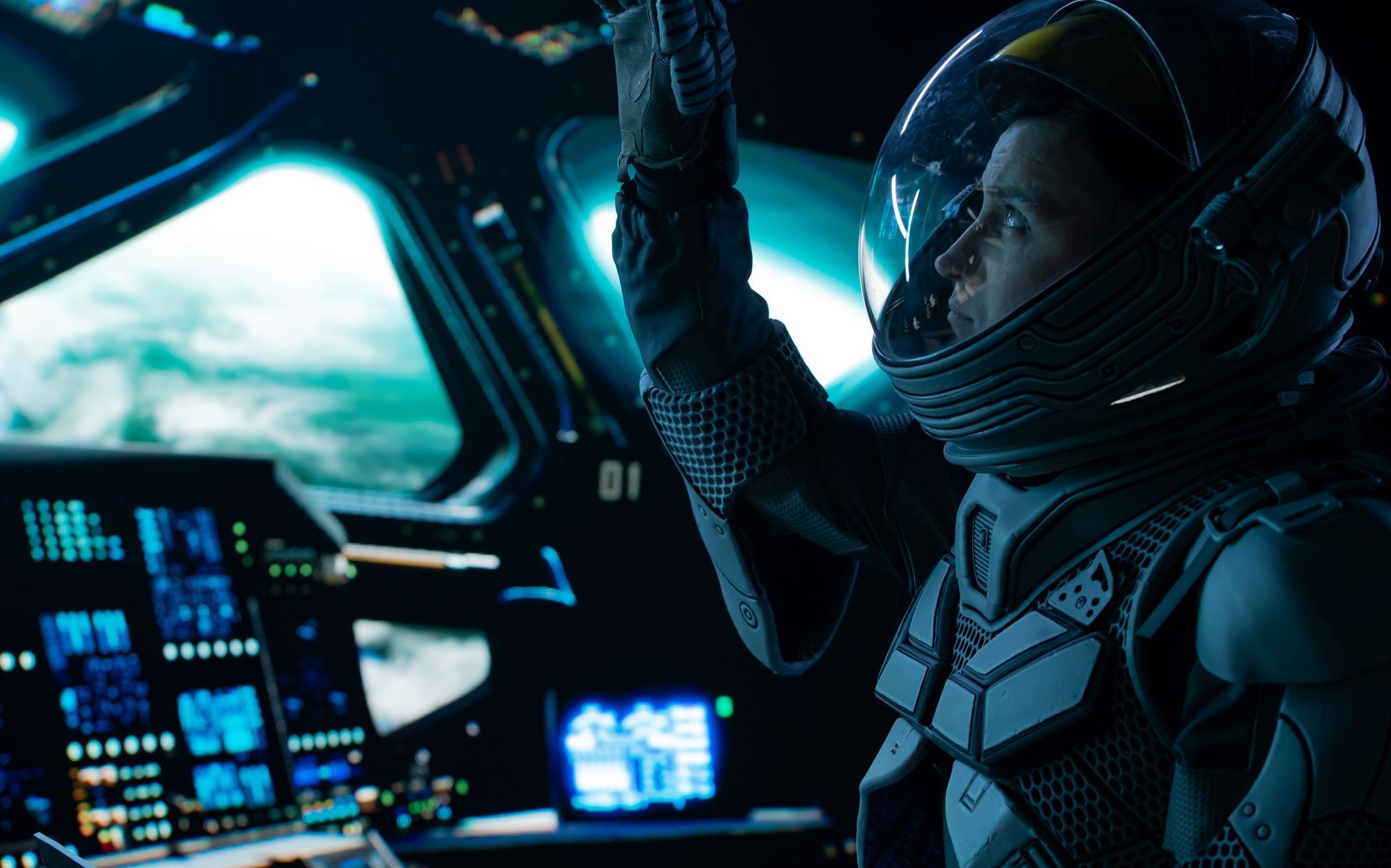 Zu sehen ist ein Astronaut, der im Cockpit einer Rakete sitzt und nach oben an einen Schalter greift. Man sieht außerdem verschiedene Displays, im Hintergrund ist durch die Fenster des Raumschiffs die Erde schemenhaft zu erkennen.